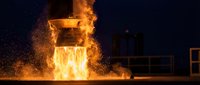 Molten metal pours from industrial furnace creating dramatic flames and sparks in foundry at night for manufacturing and metallurgy concepts.