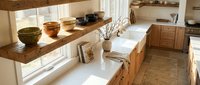 Modern rustic kitchen interior with wooden cabinets, butcher block countertops, ceramic bowls and natural lighting for home design projects.