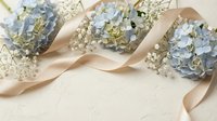 Blue hydrangeas and baby's breath flowers with a beige satin ribbon on a light textured background, copy space for wedding or event design.