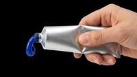Hand squeezing silver metallic tube with blue paint coming out, isolated on transparent background, ready for stickers, clipart, print on demand, and t-shirt design use.