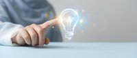 Businessman pointing at glowing lightbulb hologram representing innovation, creativity and bright ideas for business solutions and strategic planning.