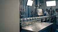 Modern pharmaceutical manufacturing facility with stainless steel equipment and glass vials on production line for medical industry automation.