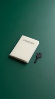 Cream passport and dark key on teal background, symbolizing travel security and immigration documentation for tourism, vacation planning and international journey concepts.
