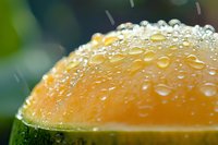 Macro shot of fresh orange fruit with water droplets on surface, showcasing natural texture and juicy freshness against blurred green background.