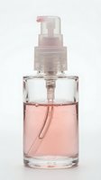 Clear glass bottle with pink liquid fragrance and pump dispenser on white background, suitable for cosmetics, perfume, skincare product packaging design.