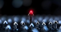 Glowing red arrow stands out among white illuminated arrows on dark background, symbolizing leadership, uniqueness and standing apart from competition.