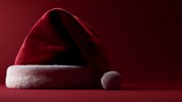 Traditional red Santa Claus hat with white fur trim on deep red background, creating festive holiday atmosphere for Christmas season designs.