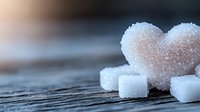 Sugar crystals and heart-shaped candy on wooden surface. Suitable for food, confectionery, baking, and sweet treat marketing materials.