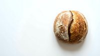 Freshly baked artisan sourdough bread loaf with golden crust on white background. Homemade bakery product for food photography and culinary designs.