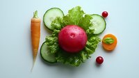 Fresh red apple on green lettuce leaf with cucumber slices, carrot, cranberries and mandarin arranged on light background. Clean eating concept for healthy diet.