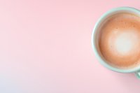 Minimalist coffee cup with creamy latte art on pastel pink and blue gradient background, top view composition with copy space for text placement.