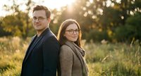 Happy young Caucasian couple wearing glasses standing back to back outdoors in golden sunset light. Professional business portrait for lifestyle marketing.