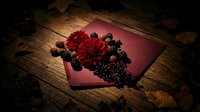 Dark romantic composition with red flowers and blackberries spilling from burgundy envelope on rustic wooden surface for gothic wedding invitations.