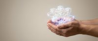 Hands holding glowing transparent gift box with ribbon bow, magical present concept for holidays, celebrations and special occasions.