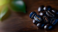 Freshly roasted dark coffee beans scattered on wooden surface with soft natural lighting and shallow depth of field creating moody atmosphere.