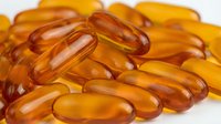 Amber-colored gel capsules and softgel supplements arranged on white background, representing vitamins, omega-3, fish oil, or nutritional health products for wellness and medical purposes.