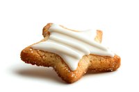Star-shaped sugar cookie with white frosting icing on top, isolated on white background for easy design integration. Festive holiday baking treat.