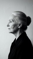 Senior woman with gray hair in bun, wearing black blazer, shown in profile against white background. Suitable for business, corporate, and professional design projects.