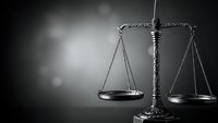 Scales of justice on dark background with dramatic lighting for legal concepts and law firm presentations.