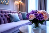 Fresh pink and purple roses in glass vase on marble table, elegant living room interior with luxurious violet velvet sofa and decorative pillows in modern home setting.