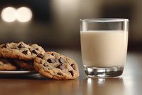 Fresh baked chocolate chip cookies on wooden table with glass of milk, warm bokeh background creates cozy atmosphere for comfort food concept.
