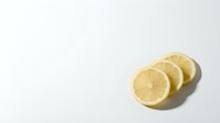 Three fresh lemon slices arranged on a clean white background with soft shadows, showcasing vibrant citrus texture for food and health projects.