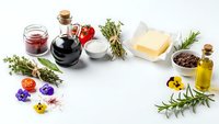 Culinary ingredients and cooking essentials arranged on white background with herbs, oils, vinegar, butter, spices and condiments for gourmet recipes.