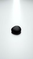 Single black smooth river stone on white background for spa wellness meditation and zen concepts.