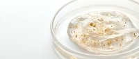 Luxurious golden face scrub with exfoliating particles in glass jar on white background, spa skincare treatment for glowing skin and beauty routine.