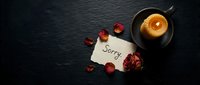 Handwritten sorry note beside a dried rose, scattered petals, and glowing candle on dark slate, evoking apology, regret, and reconciliation.