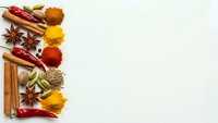 Colorful spices and herbs arranged on white background with copy space for culinary design projects and cooking content.