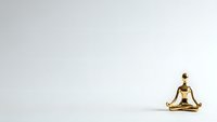 Golden meditation figurine in lotus pose on clean white background for wellness and mindfulness design projects.