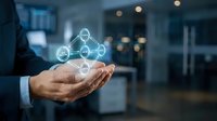 Businessman holding glowing network connection icons in cupped hands representing digital connectivity, teamwork and business collaboration concepts.