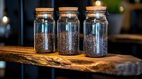 Glass storage jars with cork lids filled with roasted coffee beans on rustic wooden shelf, warm ambient lighting creates cozy cafe atmosphere.