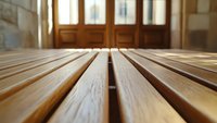 Close-up of wooden slats on floor with warm sunlight streaming through doors, creating atmosphere of tranquility in interior space.