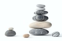 Balanced stack of zen stones on white background, featuring smooth river pebbles in grey and beige tones. Minimalist composition for wellness and spa designs.