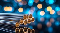 Metallic tubes or pipes arranged in rows with golden reflective surfaces against blurred blue and orange bokeh lights background creating modern industrial composition.
