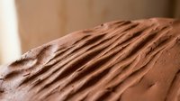 Close-up of rich chocolate frosting with decorative ridged texture on cake surface, showing smooth creamy consistency for bakery and dessert applications.