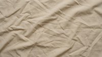 Crumpled beige linen fabric with natural wrinkles and folds, suitable for textile, fashion, and interior design backgrounds.