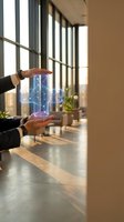 Businessman hands protecting holographic digital network cube in modern office corridor with natural light and contemporary interior design.