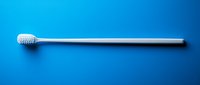 White plastic toothbrush with soft bristles isolated on vibrant blue background, minimalist composition for dental hygiene and oral care advertising.