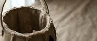 Burlap sack with rich dark soil spilling out on rustic wooden surface, perfect for gardening and agricultural projects.
