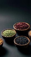 Wooden bowls filled with assorted legumes including red kidney beans, green split peas, and black beans on dark surface for cooking and nutrition content.