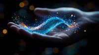 Magical glowing blue and orange particles floating above open palm against dark background with bokeh lights, creating ethereal wave pattern of sparkling dust.