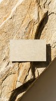 Blank business card mockup on textured sandstone wall with natural shadows for branding and corporate identity design projects.
