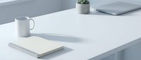 Minimalist workspace with white mug, notebook, and potted plant on clean desk, ideal for business and office design projects.