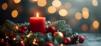 Festive red candle surrounded by pine branches, ornaments, and berries with soft bokeh lights creating warm holiday atmosphere.