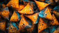 Orange triangular shapes with holes and blue patina texture create abstract geometric pattern on dark background, macro photography for artistic design projects.