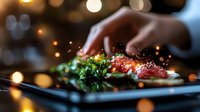 Chef garnishing fresh salmon dish with herbs and spices on dark plate against blurred bokeh lights background, close up view of culinary preparation.
