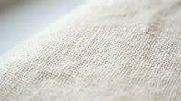 Natural linen fabric texture with woven fibers in soft beige tones, showcasing organic textile material for interior design and craft projects.